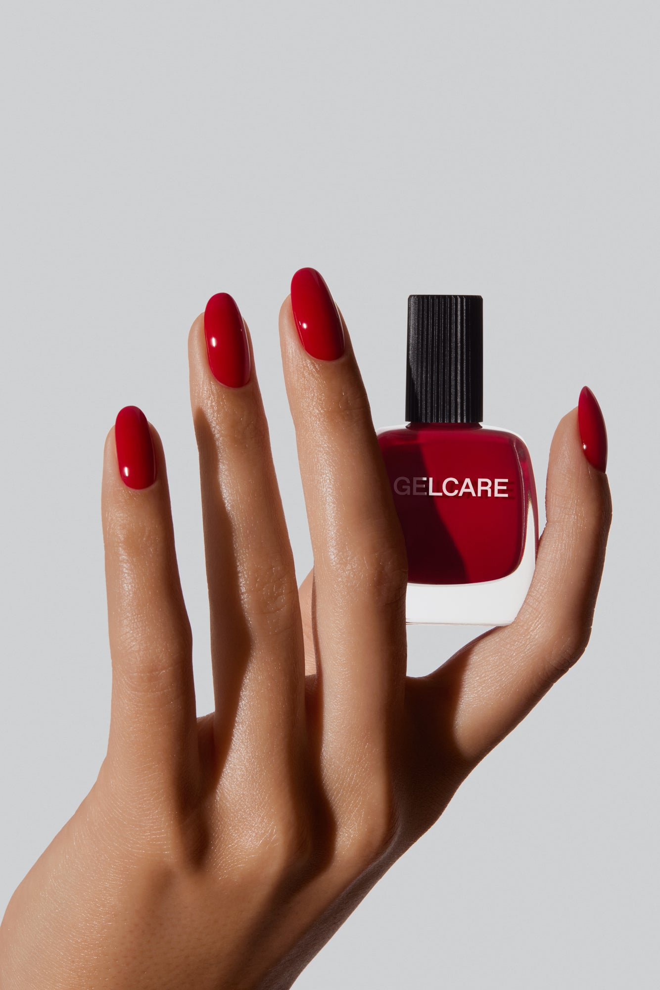 Bouteille de vernis rouge morello Gelcare dans une main