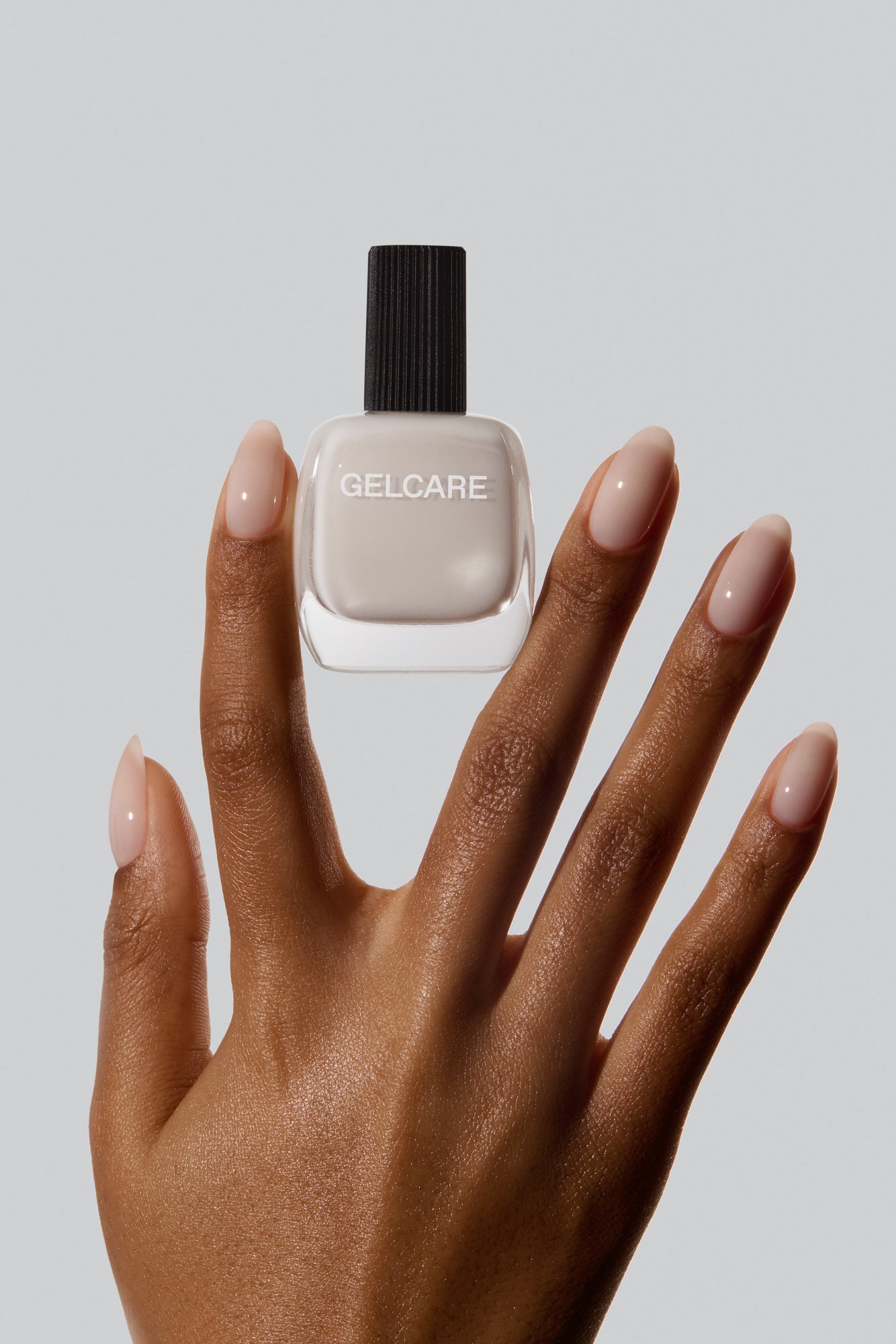 Bouteille de vernis blanc cassé Gelcare dans une main