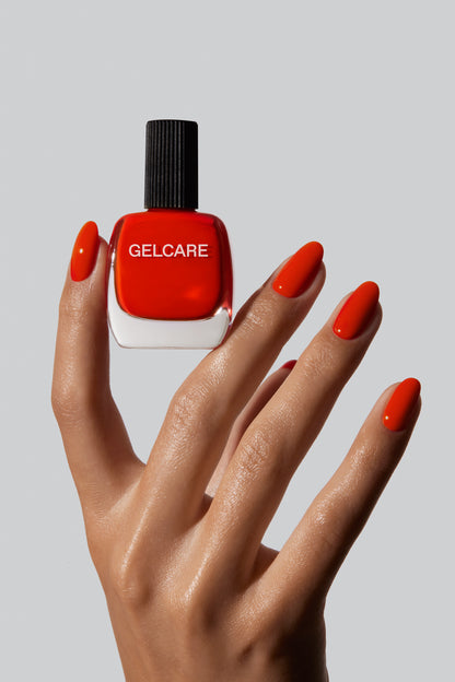 Bouteille de vernis corail Gelcare entre les doigts d'une main