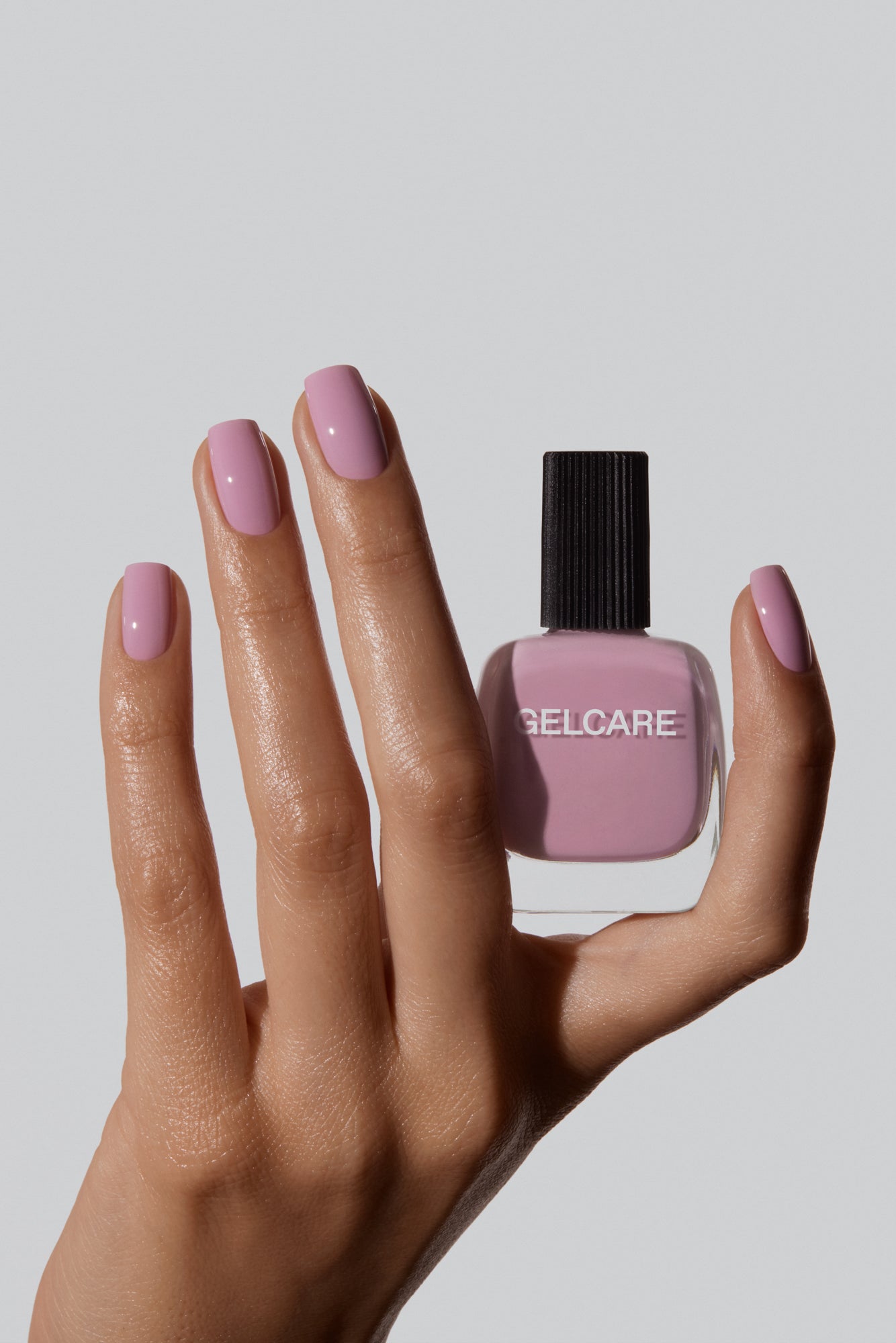 Bouteille de vernis rose English Gelcare dans une main