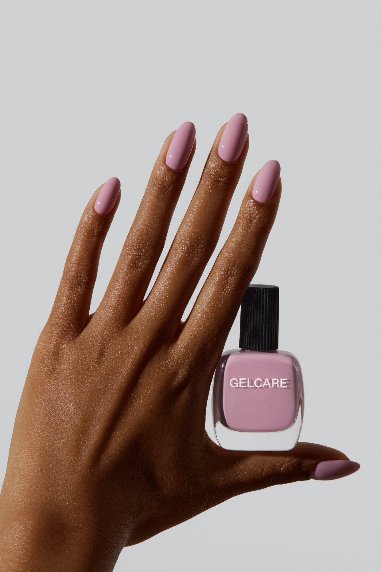 Bouteille de vernis rose English Gelcare entre les doigts d'une main