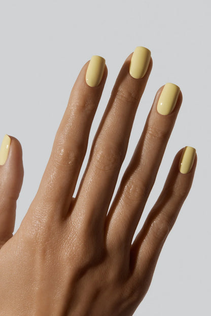 Main avec les ongles vernis jaune beurre Gelcare