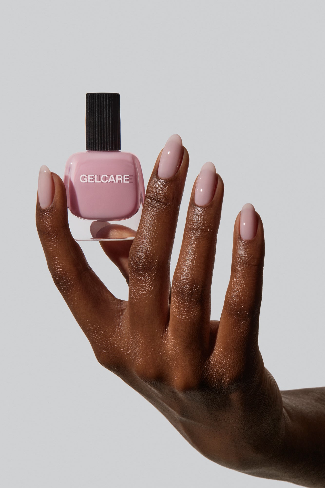 Bouteille de vernis rose bb cream Gelcare dans une main