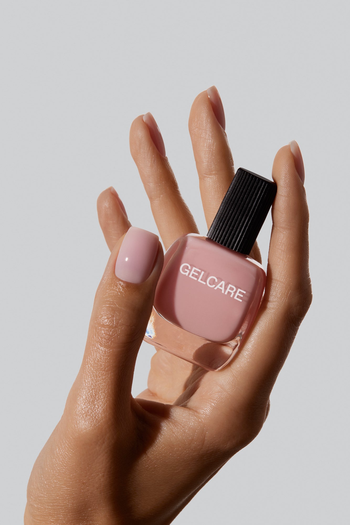 Bouteille de vernis rose pâle Gelcare dans une main