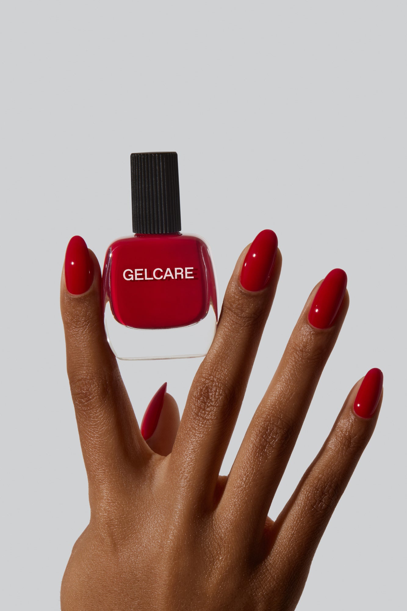 Boutille de vernis rouge Gelcare entre les doits d'une main