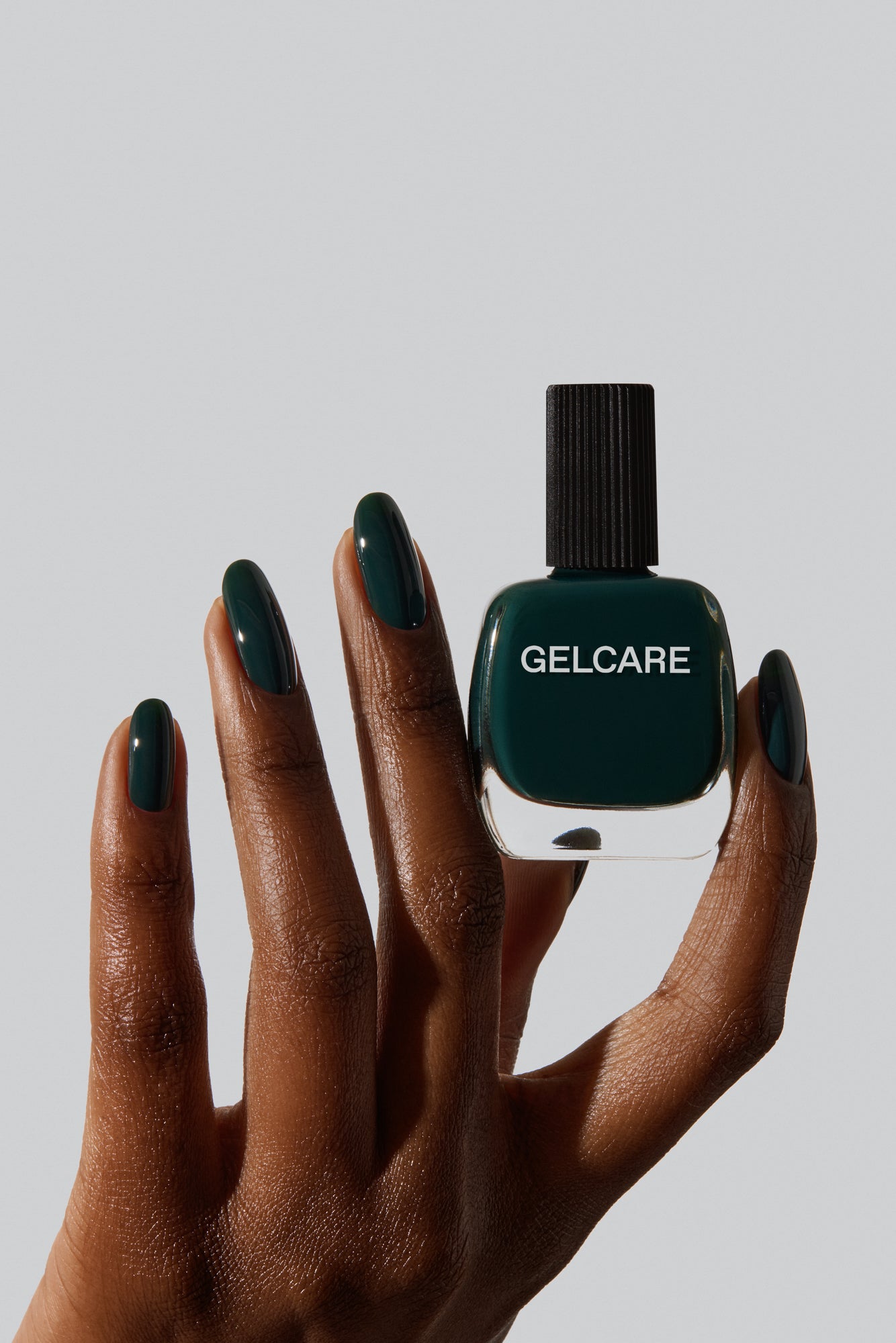 Bouteille de vernis vert foncé Gelcare dans une main