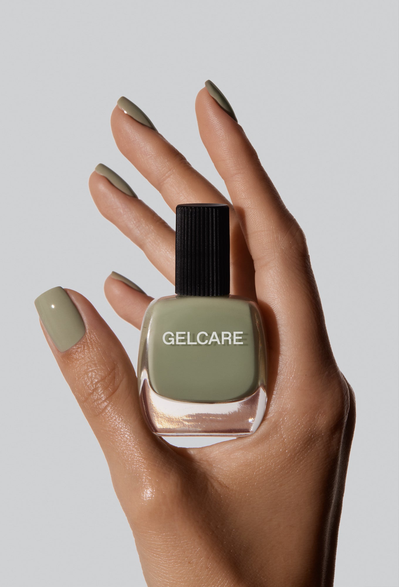 Bouteille de vernis vert sauge herbal Gelcare dans une main