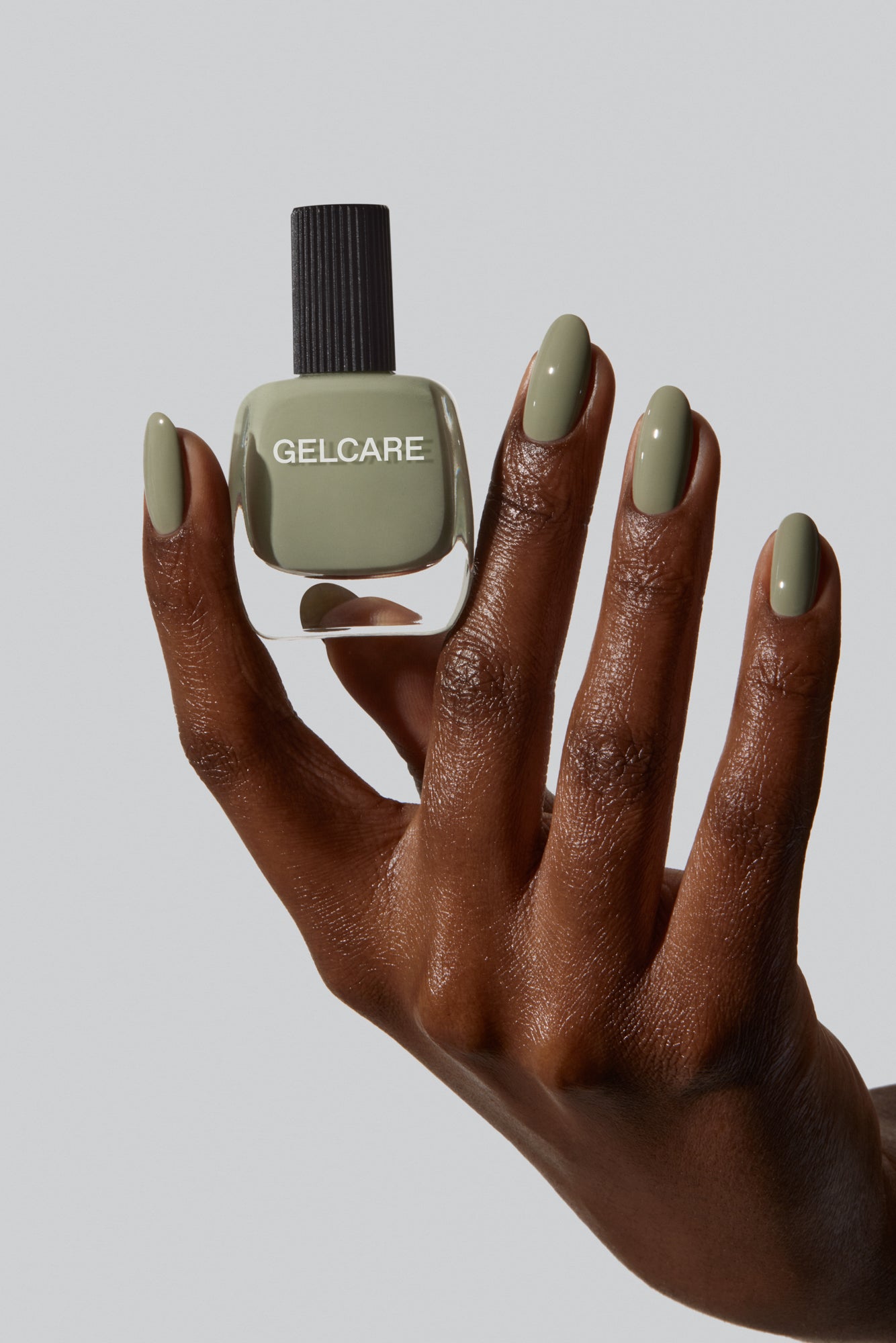 Bouteille de vernis vert sauge herbal Gelcare entre les doigts d'une main